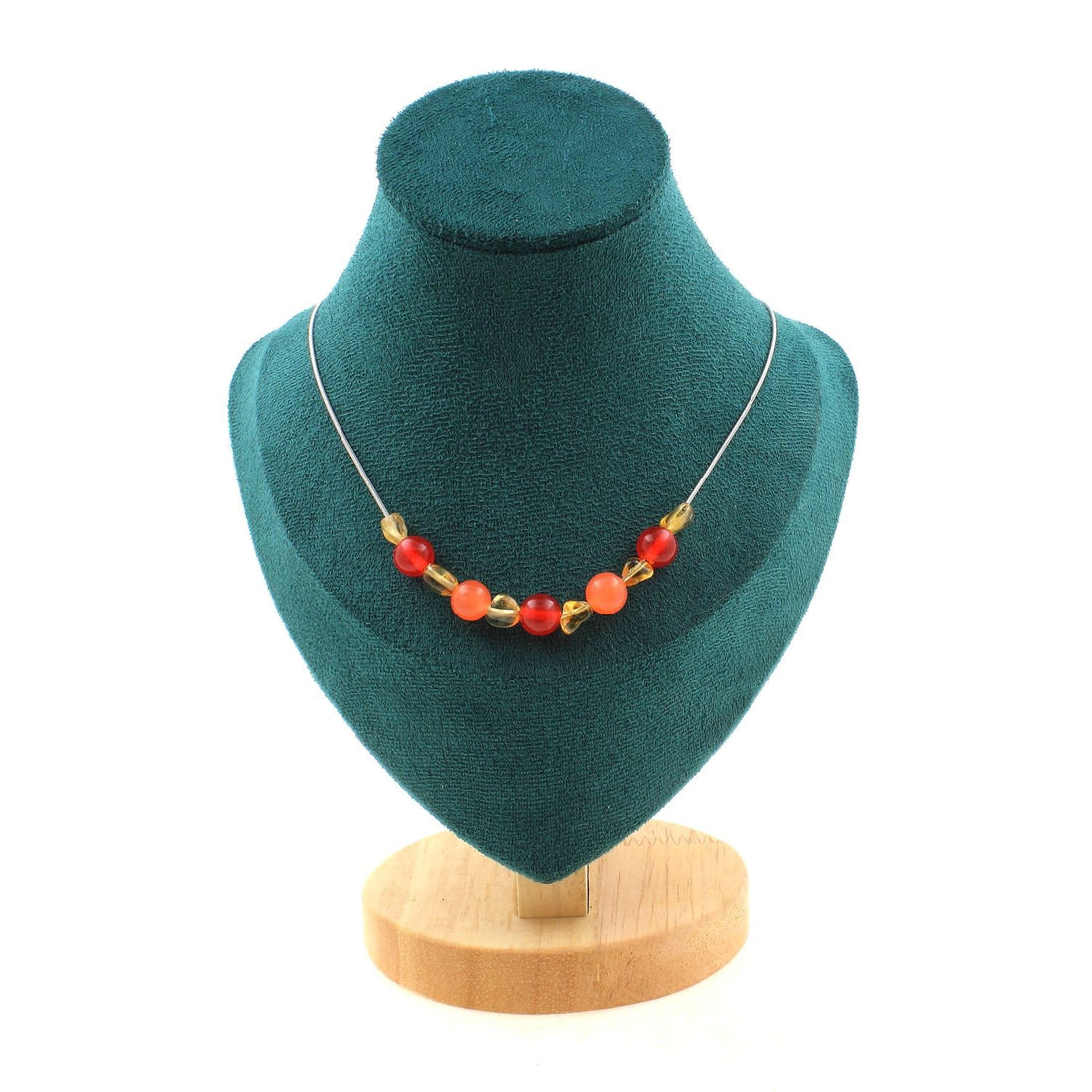 Necklace with red and orange beads on a teal display stand with a wooden base.