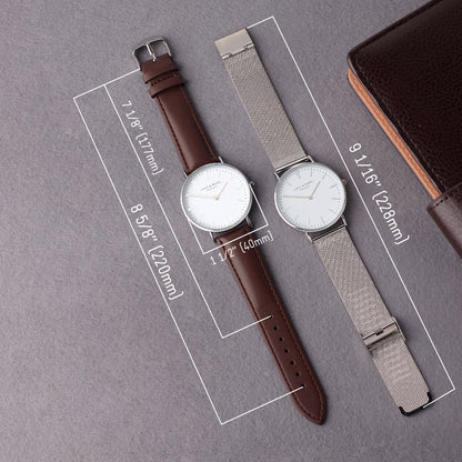 Two minimalist watches: one with a brown leather strap, the other with a silver mesh strap, on gray.