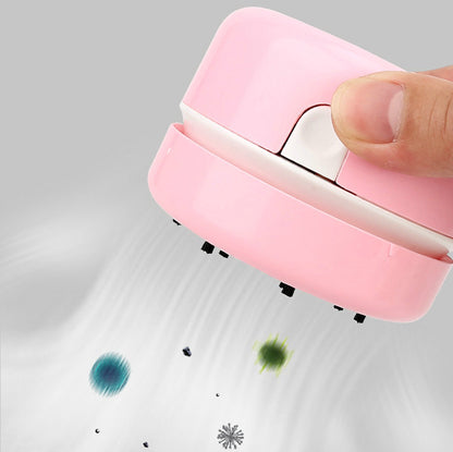 Pink handheld vacuum cleaner removing colorful dust on a gray surface.