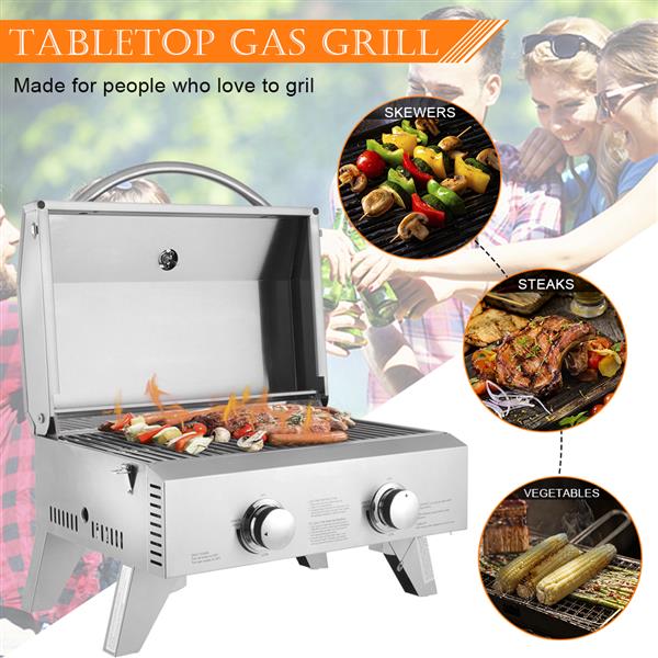 Silver tabletop gas grill with open lid; skewers, steaks, and vegetables cooking on grate.