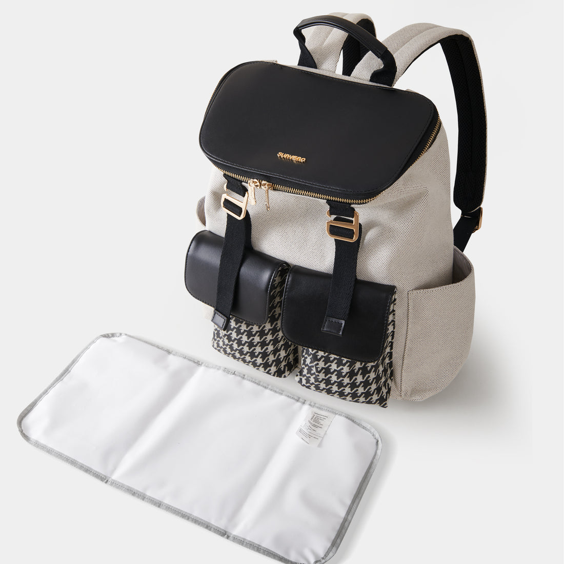 Beige backpack with black flap, gold buckles, houndstooth pockets, and a white changing mat.