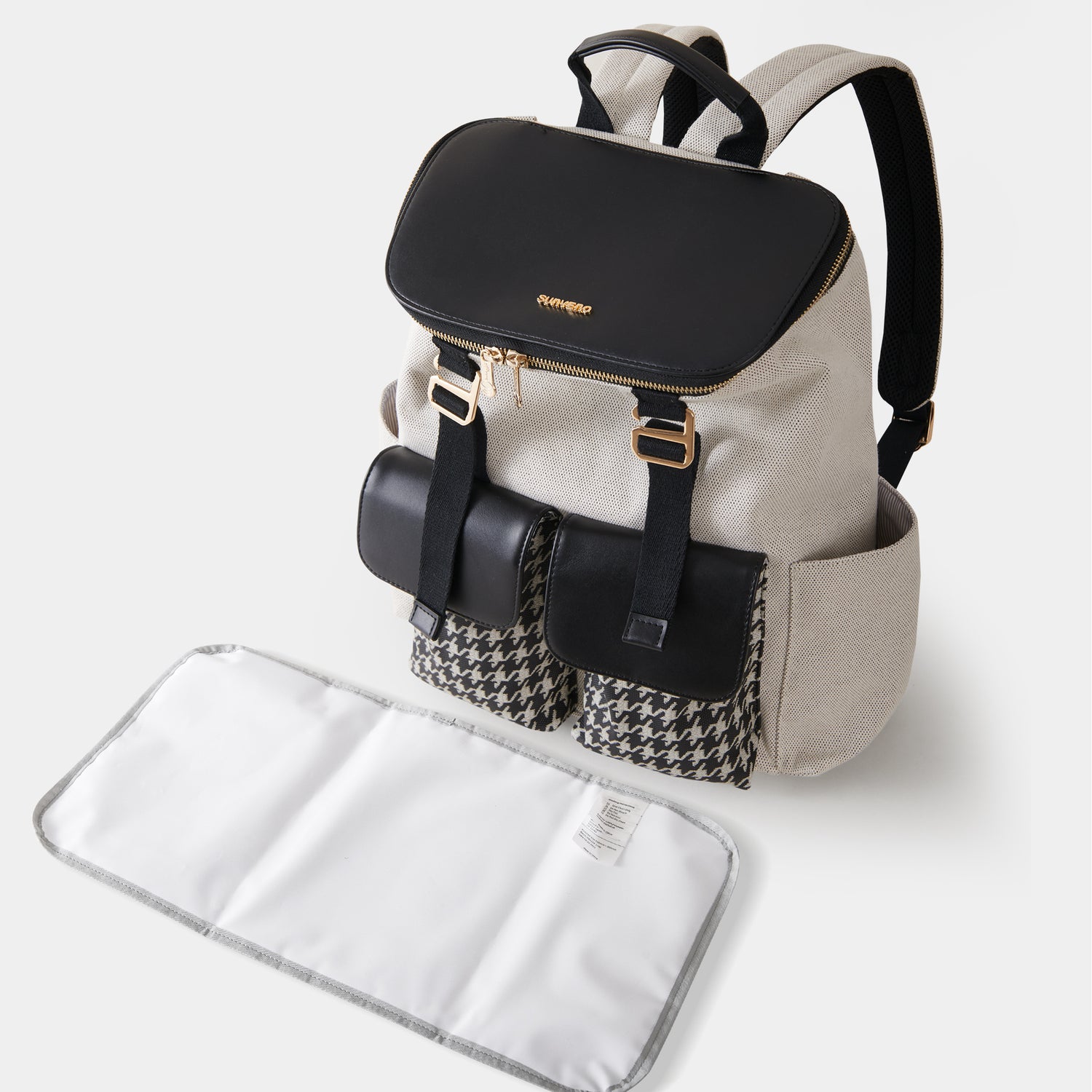 Beige backpack with black flap, gold buckles, houndstooth pockets, and a white changing mat.