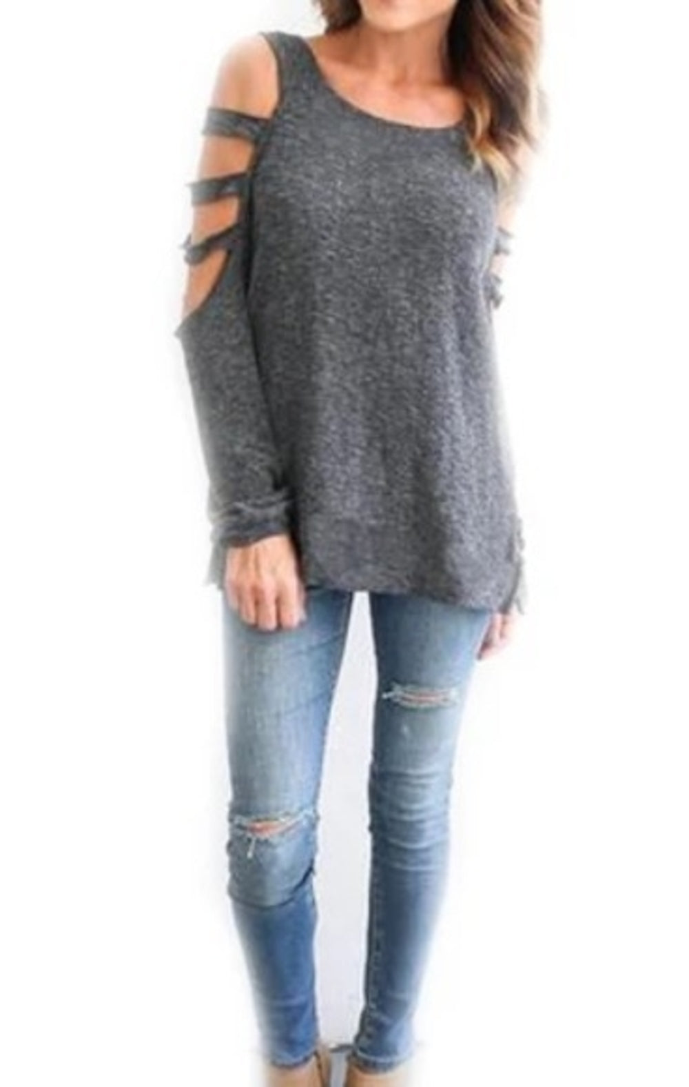 Woman in a grey cold-shoulder top and ripped blue jeans against a white background.