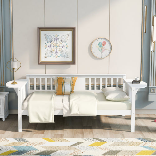 White daybed with plaid pillow, beige blanket, floral artwork, clock, and modern lamp on side tables.