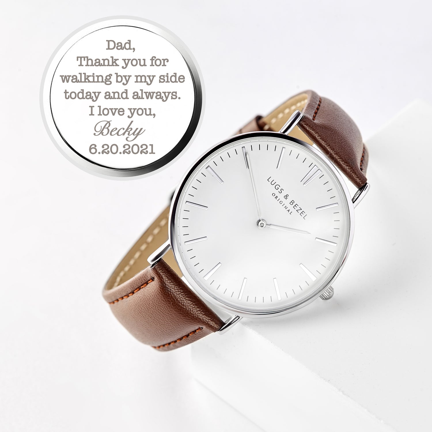 Brown leather strap watch with white face engraved with a personal message inside the case.