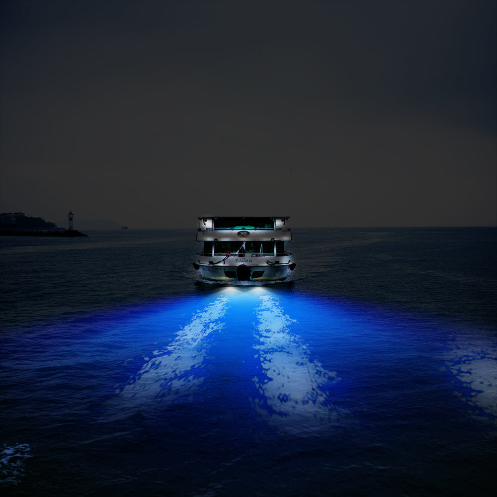 A brightly lit boat on dark water, casting vivid blue reflections behind it.