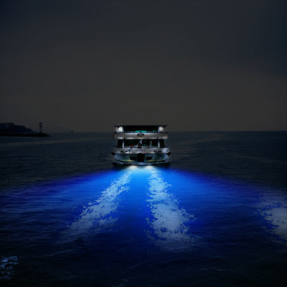 A brightly lit boat on dark water, casting vivid blue reflections behind it.