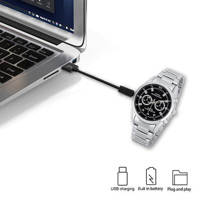 Silver watch with black dial connected to a laptop via USB cable, with charging icons below.