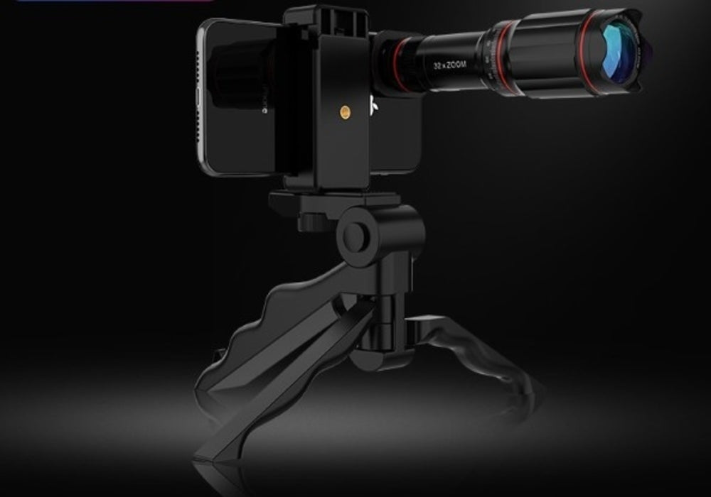 Smartphone with a zoom lens mounted on a black tripod, set against a dark background.