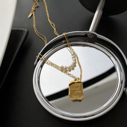 A gold necklace with pearls and a pendant on a small round mirror, reflecting its elegant design.