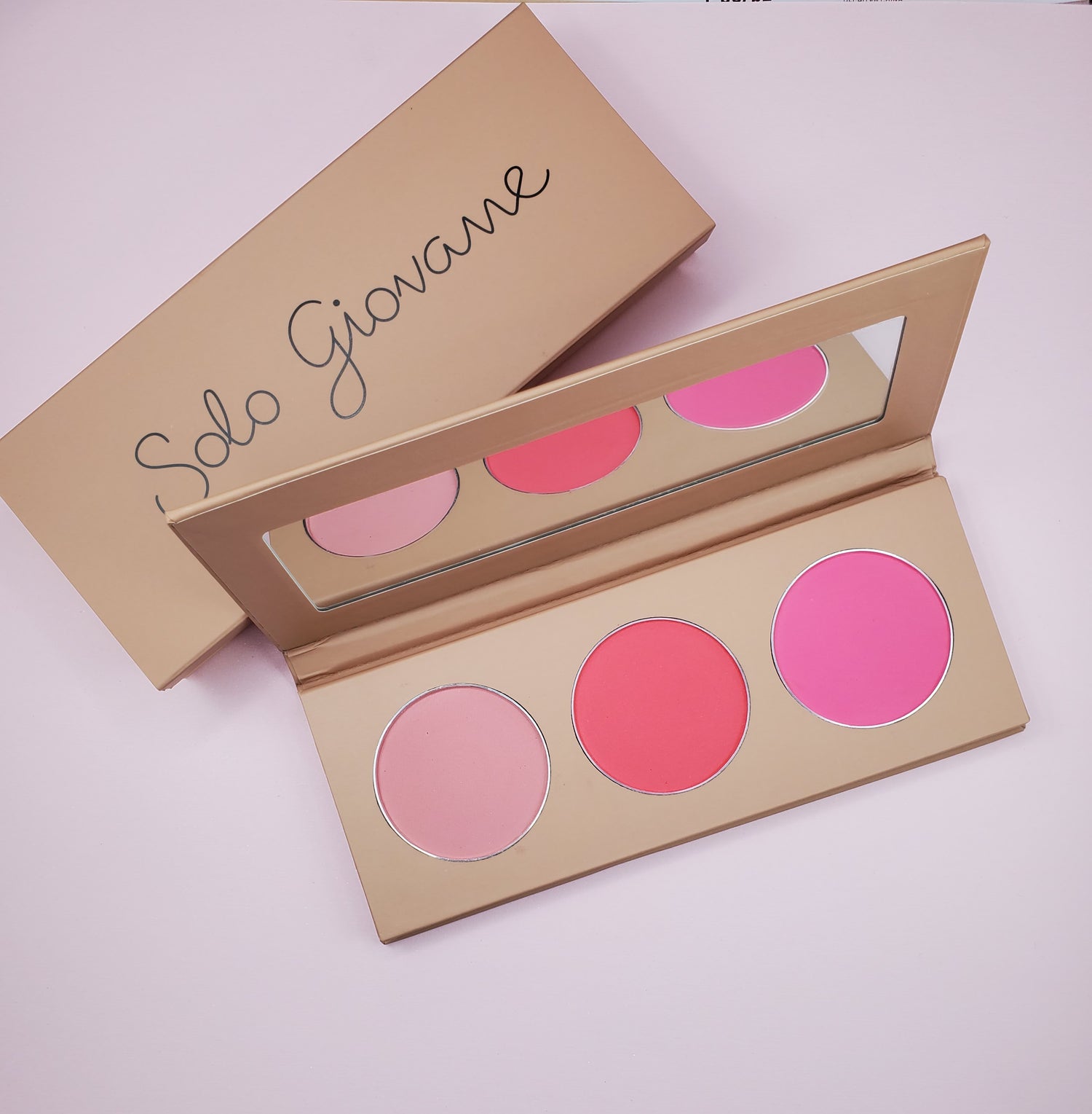 Makeup palette with three pink shades, a beige case, and a mirror inside.
