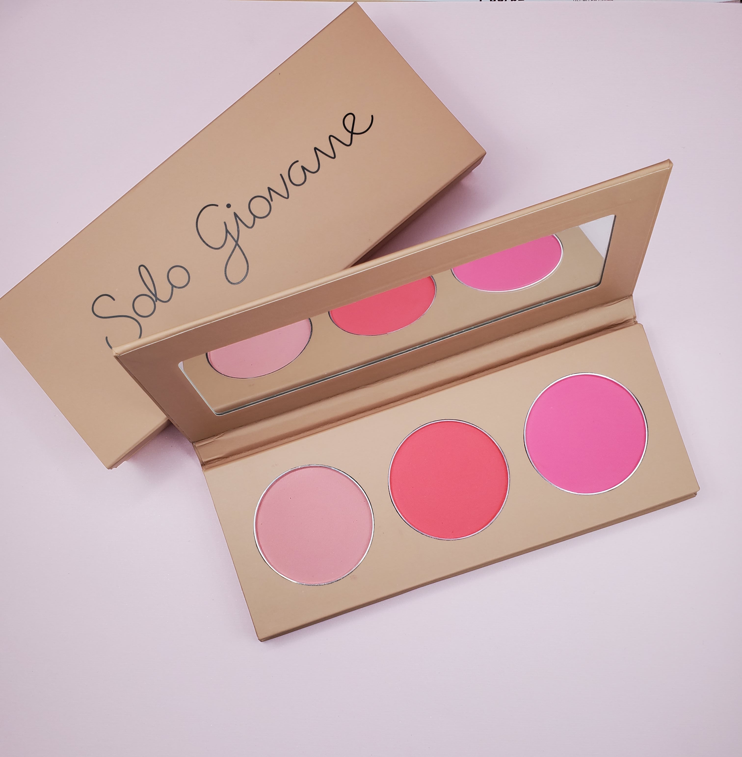 Makeup palette with three pink shades, a beige case, and a mirror inside.