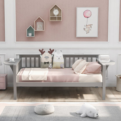 Gray daybed with pink bedding, animal pillows, pink wall, and decorative shelves.