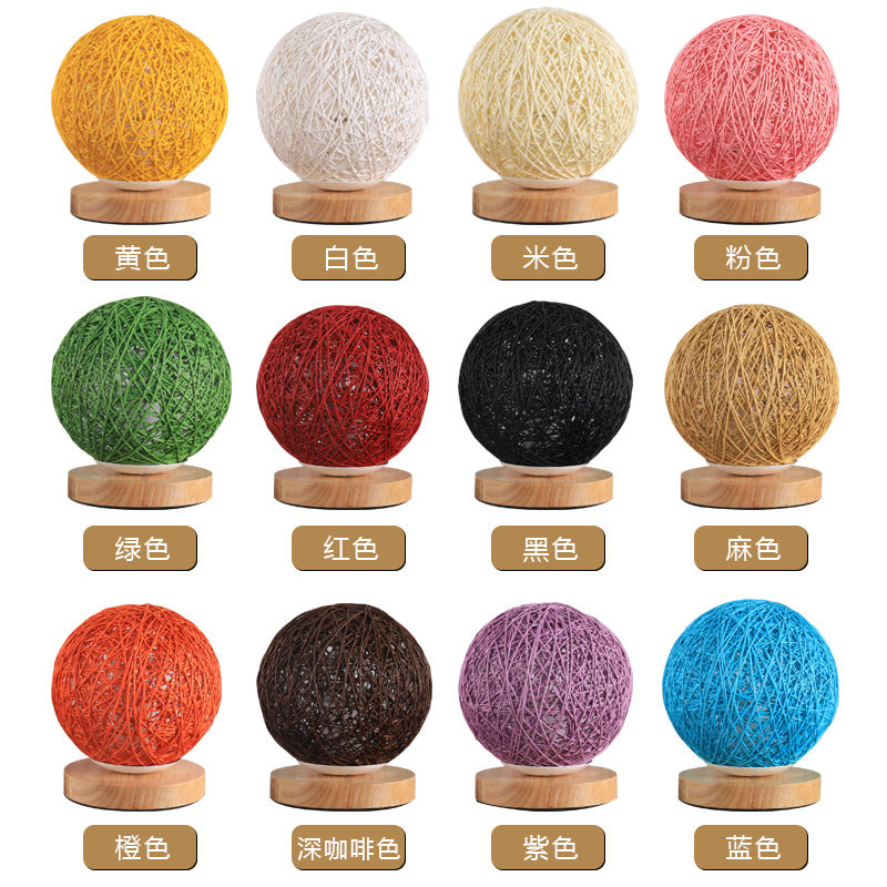 Twelve colored string light balls on wooden bases in yellow, white, cream, pink, green, red, black, and more.