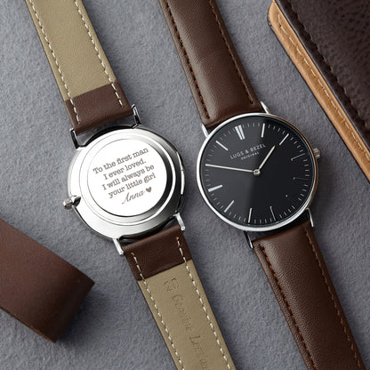 Two watches with brown leather straps; one shows black face, other shows engraved message.