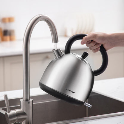 Stainless steel kettle being filled with water from a faucet in a modern kitchen setting.