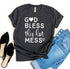 Dark gray shirt with white text "God Bless This Hot Mess," paired with blue jeans and black flats.