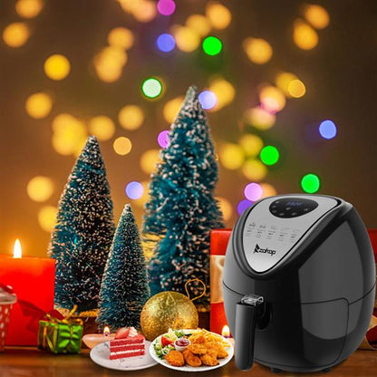 Black air fryer with Christmas lights, small trees, candles, and festive food in the foreground.