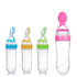 Four transparent baby bottles with colored lids and spoons: blue, orange, green, and pink.