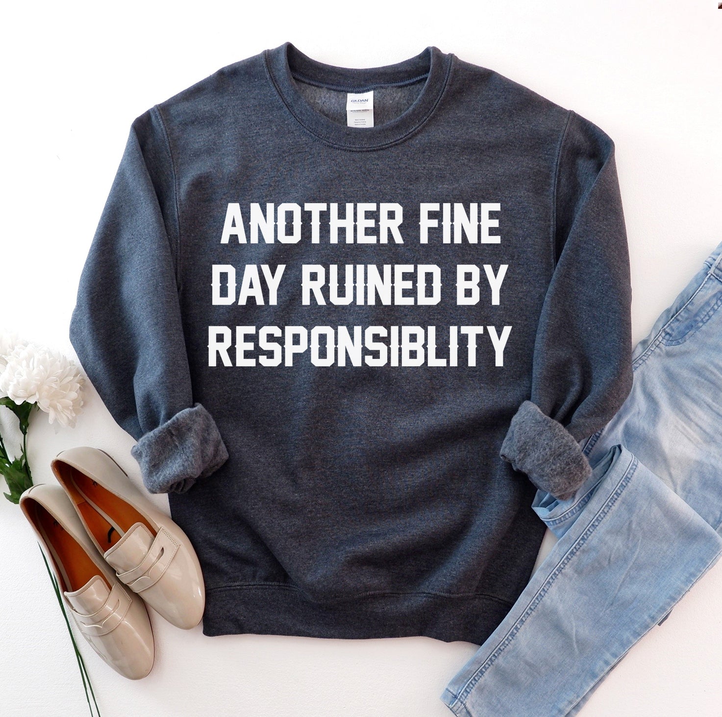 Dark sweatshirt with "Another Fine Day Ruined by Responsibility" in white text, paired with light jeans.