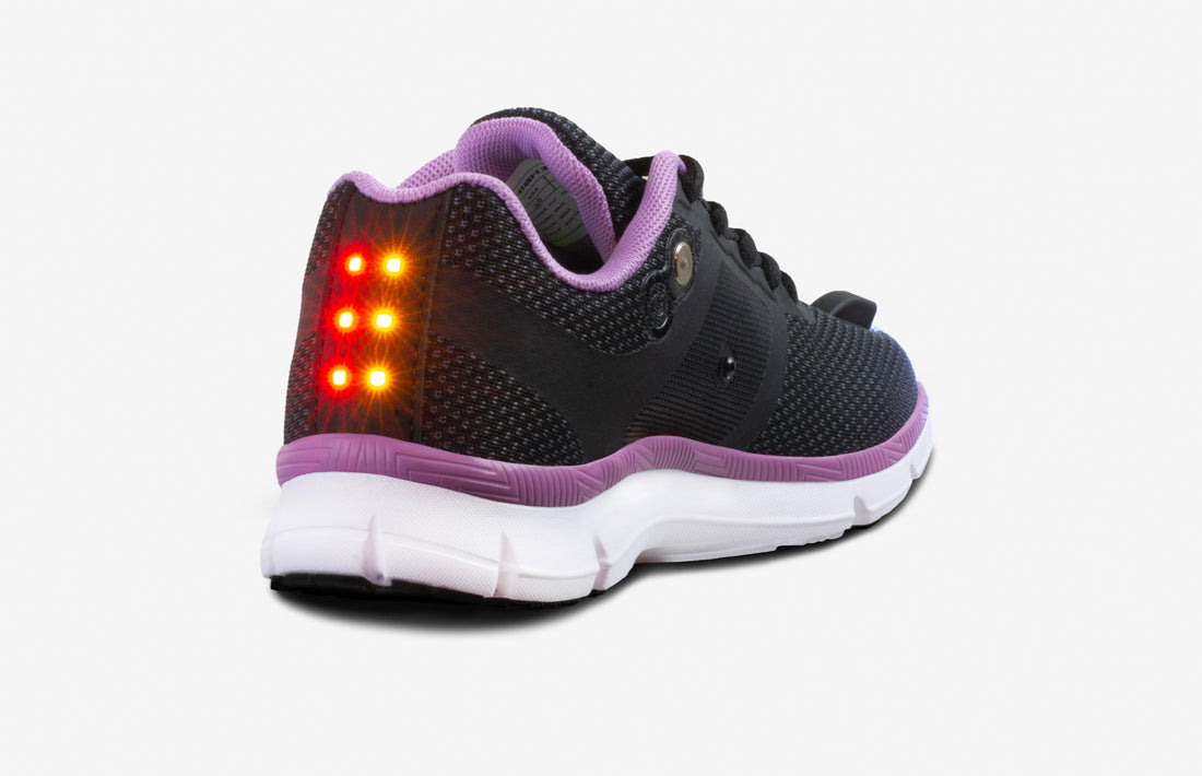 Black sneaker with purple trim and white sole, featuring rear orange LED lights.