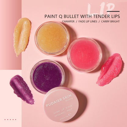 Three jars of lip scrub in yellow, pink, and purple with matching swatches on a pink background.