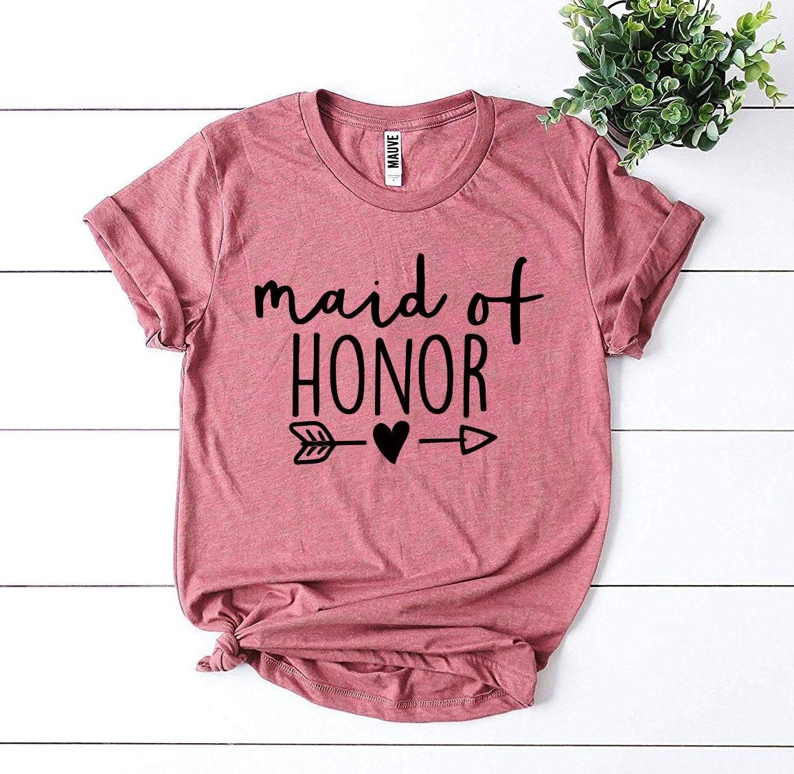 Pink t-shirt with "maid of honor" in black letters, arrow and heart design, against a white background.