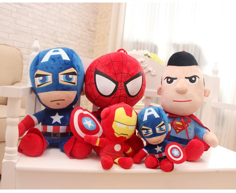 Plush toys of superheroes in bright costumes sitting on a white bench in a light room.
