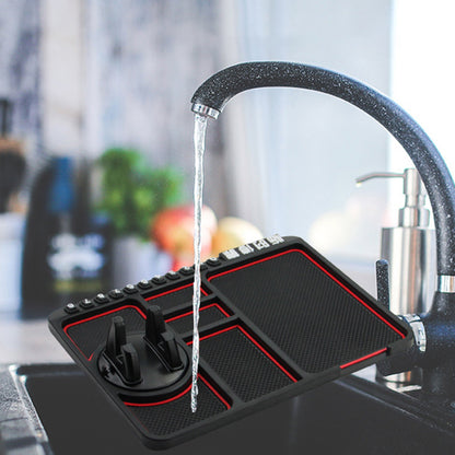 Black kitchen mat with red edges under running faucet, with a textured surface and utensil holder.