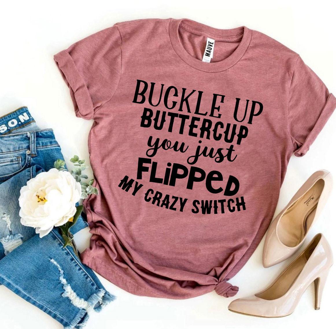 Pink T-shirt with bold black text, paired with ripped jeans, beige heels, and a white flower.