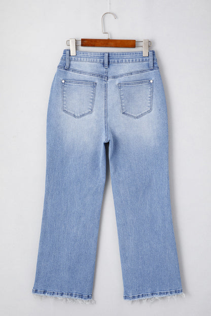 Light blue jeans with frayed hems and back patches, displayed on a hanger against a white background.