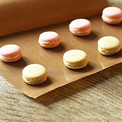 Pink and beige macarons on brown parchment paper, arranged neatly on a wooden surface.
