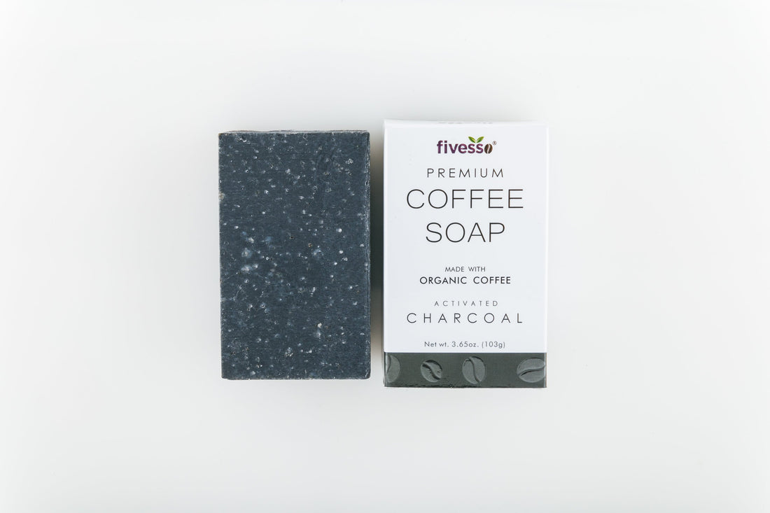 Dark speckled soap bar beside white coffee soap box with text on a light background.