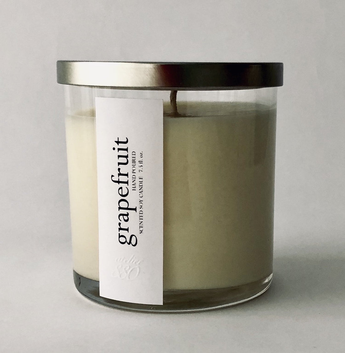 Clear glass jar candle with a silver lid and white label reading "grapefruit."
