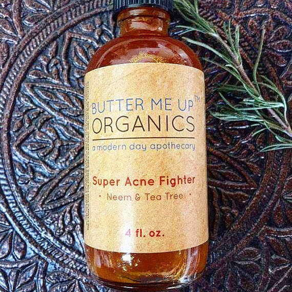 Brown bottle with a beige label reading "Super Acne Fighter Neem &amp; Tea Tree" on ornate surface.