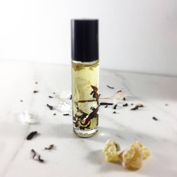 Clear bottle with black cap on white surface, containing light yellow liquid and dried herbs.