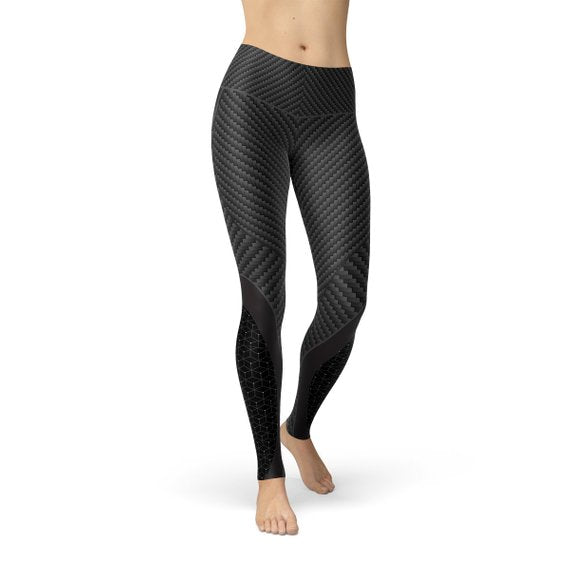 A person wearing high-waisted, textured black leggings with geometric patterns, standing barefoot.