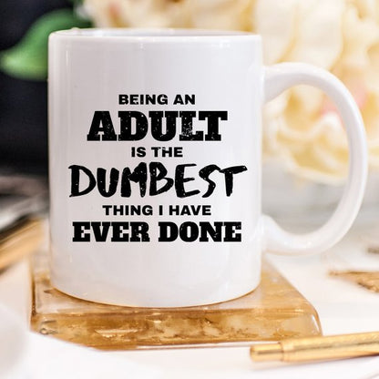 White mug with black text: "Being an adult is the dumbest thing I have ever done."