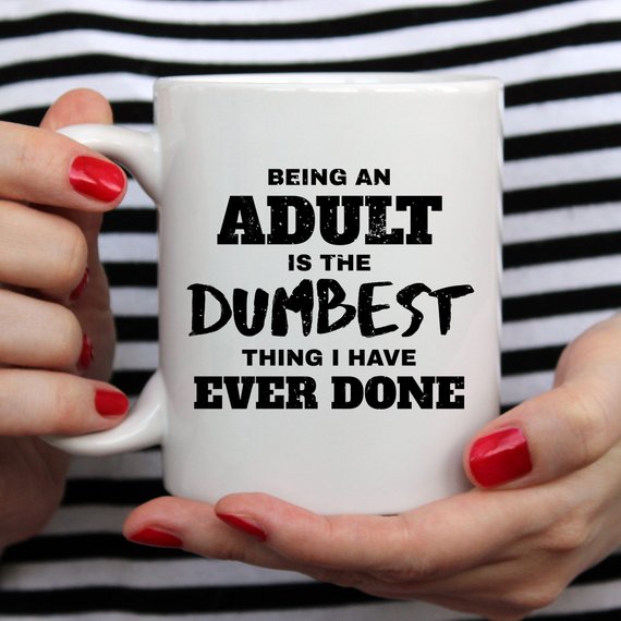 Hands with red nails hold a white mug with black text about adulthood; striped background.