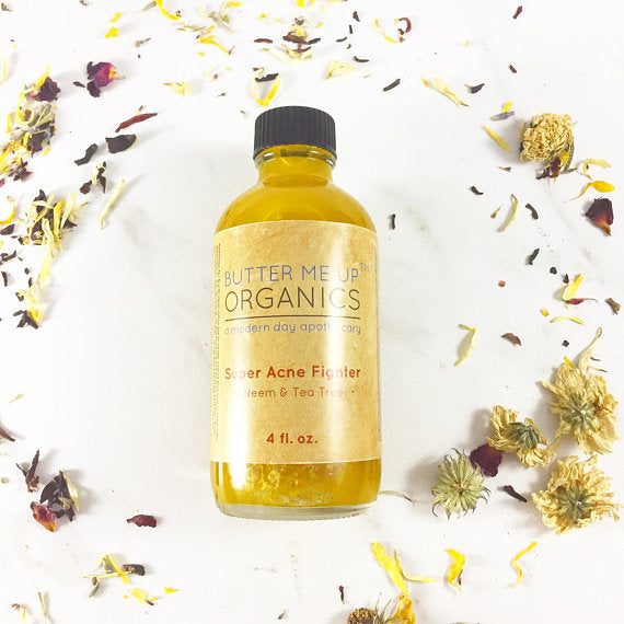 Yellow bottle with black cap on a white surface, surrounded by dried flower petals.