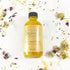 Yellow bottle with black cap on a white surface, surrounded by dried flower petals.