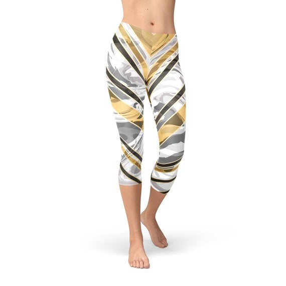 Woman wearing abstract-patterned leggings with gold, black, and white stripes, standing barefoot.