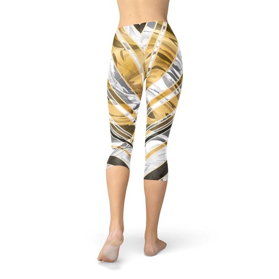 Woman wearing leggings with gold, white, and gray abstract patterns, standing barefoot.