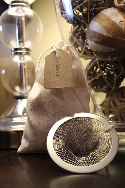 Cloth bag labeled "Soak" with a metal mesh strainer, alongside decorative wicker balls.