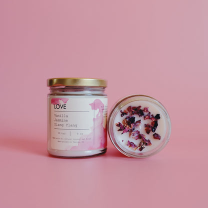 Two jars on pink background; one candle upright, the other open with dried flowers on top.