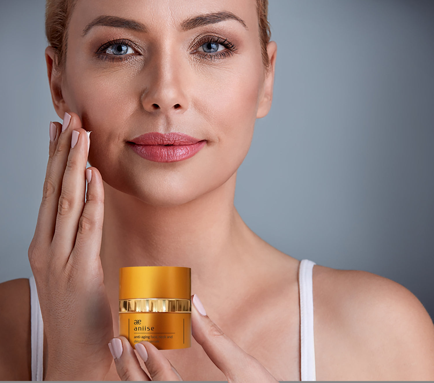 Woman applying cream to face, holding a golden jar. Soft lighting, neutral background.