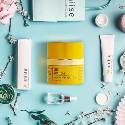 Skincare products, including yellow jar and white tubes, on a blue background with flowers.