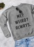 Gray sweatshirt with bold text: "ME? WEIRD? ALWAYS.", paired with sunglasses and blue jeans.