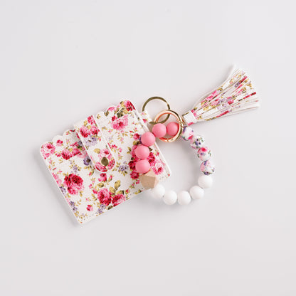 Floral cardholder with pink, white beads, and tassel keychain on white background.