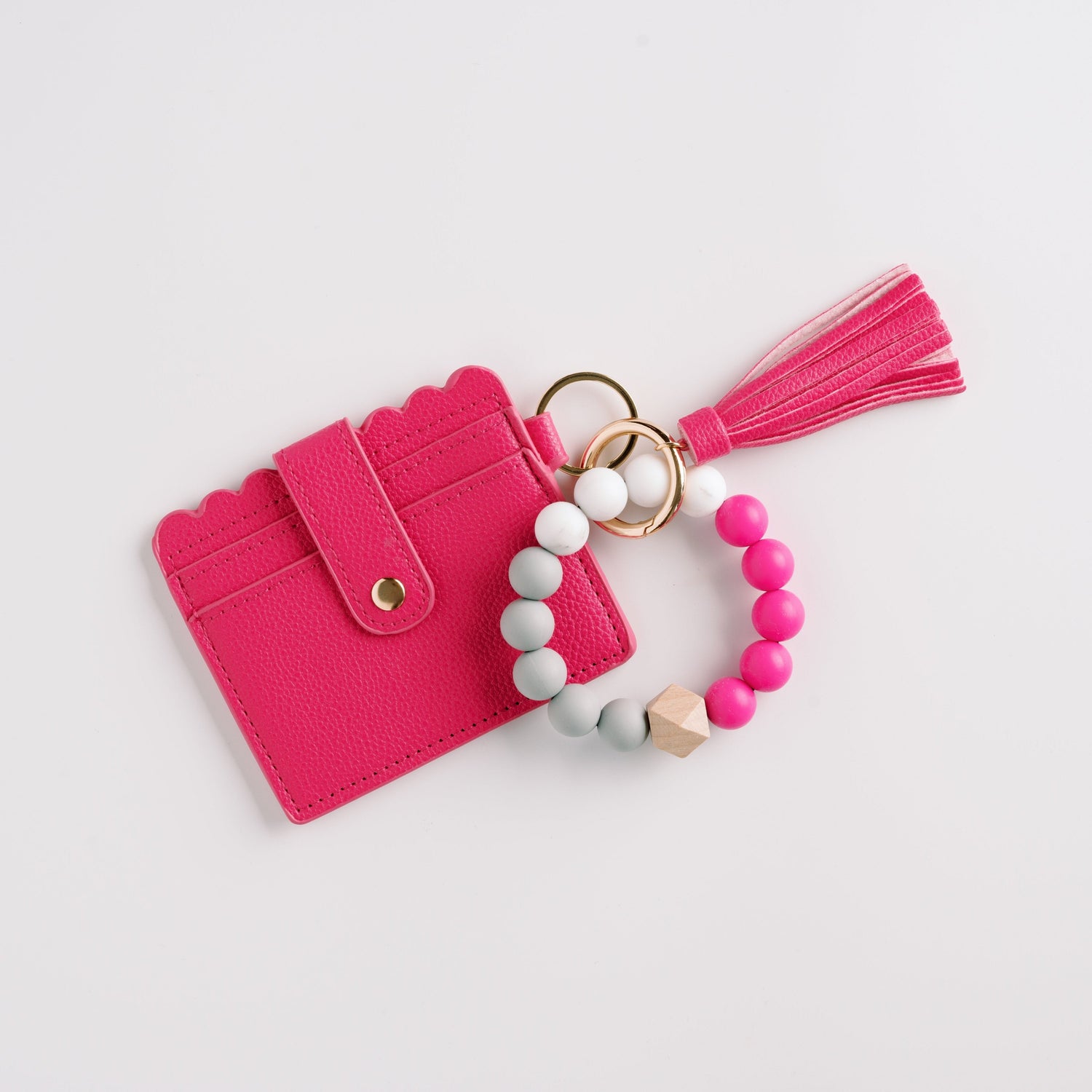 Pink cardholder with scalloped edges, attached to pink, white, and gray beaded bracelet and tassel.